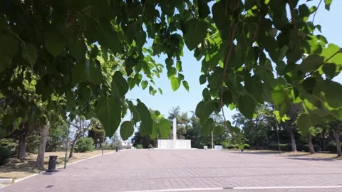 Emerging from Tree Cover Towards a Statue in Platia Miteras Park, Larissa