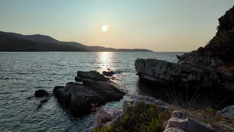 Syki Bay Coastal View at Sunset with Rolling Hills and Foreground Rocks Syki Bay Coastal View at Sunset with Rolling Hills and Foreground Rocks