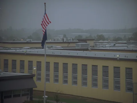35MM 2K EXT. DUSK STATE PRISON- CLOSE ON FLAG AND PRISON CELLS BLOCKS  動画素材 75364131