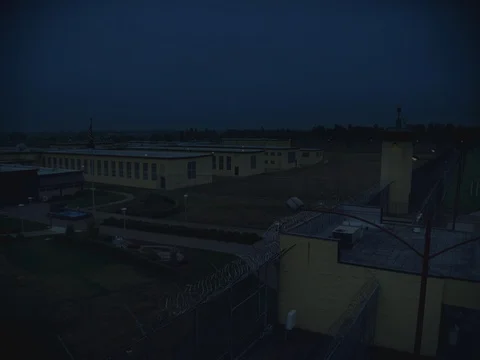 35MM 2K EXT. DUSK:NIGHT STATE PRISON- WIDE TOWER AND GROUNDS Stock Footage
