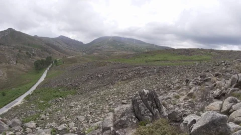 360 angle shot of field with rocks and mountains with cloudy sky Stock Footage 128962565