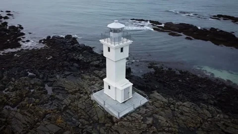 A 360 Circle Around a Tiny White Lighthouse on a Rocky Beach Video stock 145480183