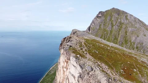 360 degree drone view of steep mountain cliffs and ocean at Brosmetinden peak Stock Footage 340504356