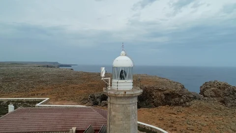 360 drone flight around a stone lighthouse on the edge of a cliff Stock Footage 116784935