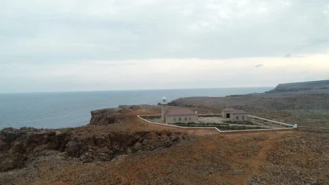 360 drone flight around a stone lighthouse on the edge of a cliff Stock Footage 116785611