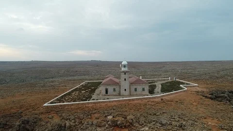360 drone flight around a stone lighthouse on the edge of a cliff Stock Footage 116785617