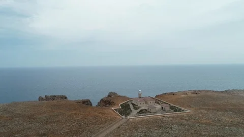 360 drone flight around a stone lighthouse on the edge of a cliff Stock Footage 116785815