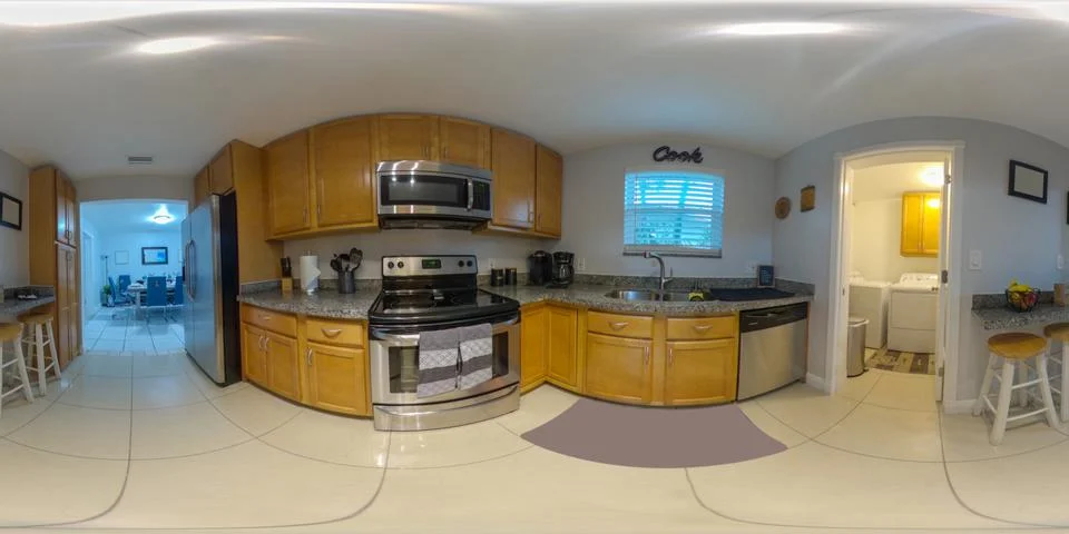 360 equirectangular photo of a kitchen with view of laundry and dining area Foto stock