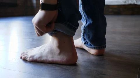 39 Guy hands closeup roll up jeans trouser leg barefoot on parquet floor Stock Footage 103435298