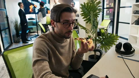 3d game artist works at a computer in the office and eats a big pizza  Stock Footage 212058392
