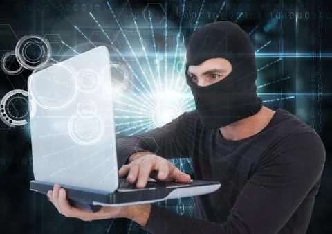 3d Hacker with hood using a laptop in front of digital background Stock Photos