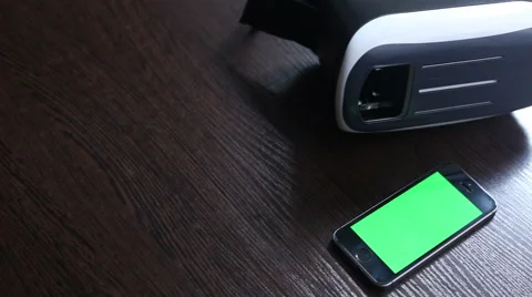 3D headset and a mobile phone on the table. Green background Stock Footage 65290140