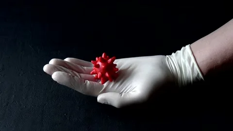 3D model of a red coronavirus lies on a hand in a white medical disposable Stock Footage 152565104