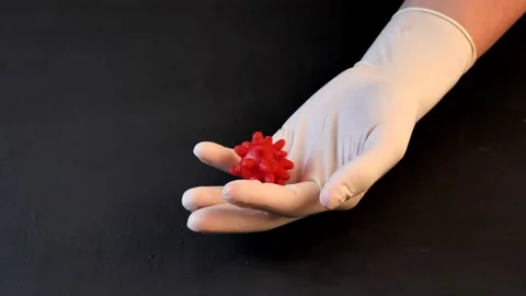 3D model of red coronavirus lies on hand in white medical disposable latex Stock Footage 152565482