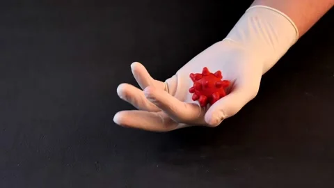 3D model of red coronavirus lies on hand in white medical disposable latex Stock Footage 152565581