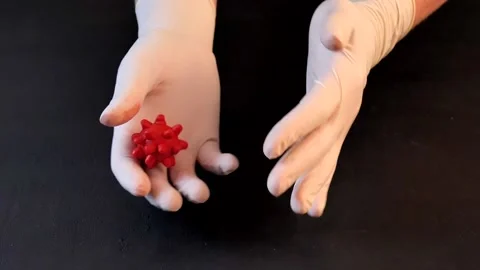 3D model of red coronavirus lies in hands in white medical disposable latex Stock Footage 152565682