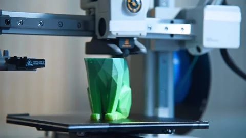 3D printer creating a green geometric cat figurine. Stockbeeldmateriaal 336198974