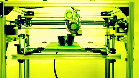 3d printer machine creating a small object in a bright workshop Stock Footage 340355991
