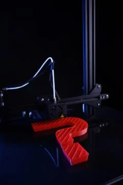 3D-printer making sculptural question mark from red plastic in blue neon light Stock Photos