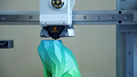3D printer nozzle creating a geometric green object. Stockbeeldmateriaal 336198939