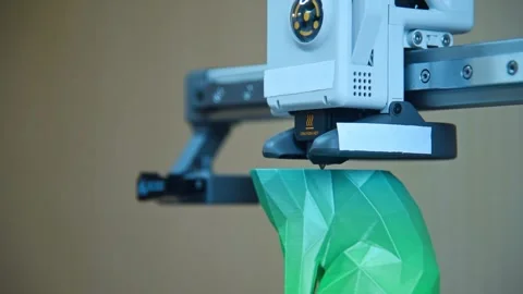 3D printer nozzle creating a green geometric object. Stockbeeldmateriaal 336198970