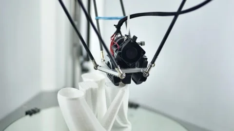 3D printer nozzle creating a white prototype object on a build plate Stock Footage 321347549