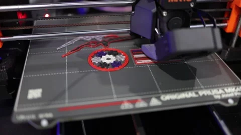 3D printer nozzle steadily builds intricate multicolor badge with gears and abst Video stock 311130955