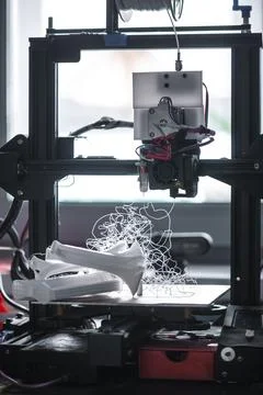 3d printer operating, creating tangled white plastic filament on the build pl Stock Photos