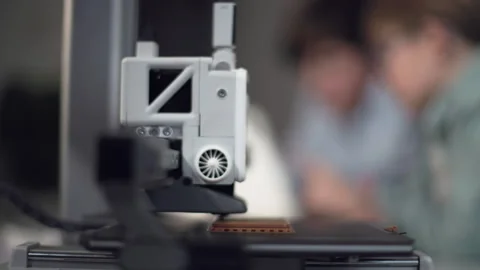 3D printer in operation in the foreground with kids on background Stock Footage 335378385