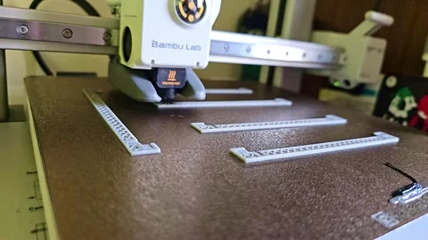 3D Printer in Operation Producing Plastic Parts on Moving Build Plate Stock Footage 323869048