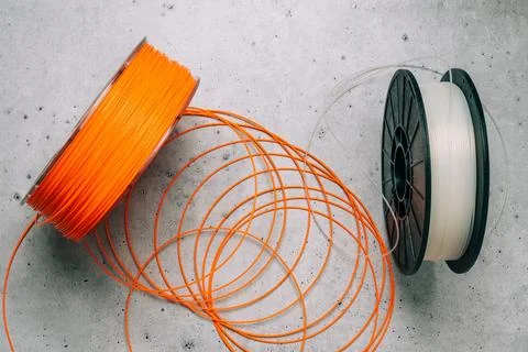 3D Printer Plastic Filaments. Spools of orange and white thermoplastic wire.. Stock Photos