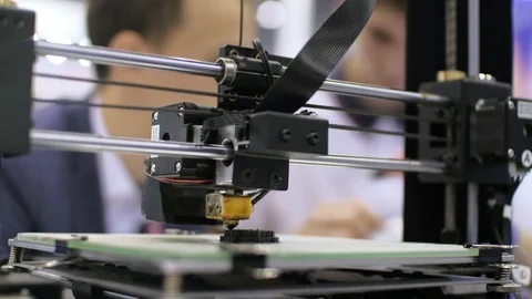 3d printer is printing detail. Two students conversation in the background. Stock Footage 94771501