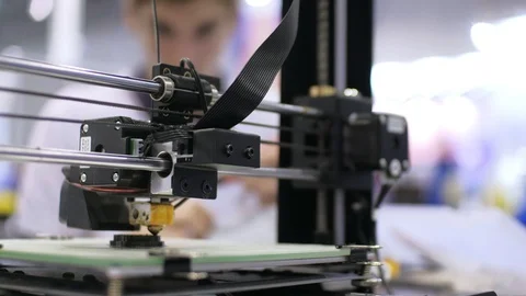 3d printer is printing detail. Two students conversation in the background. Stock Footage 94771950