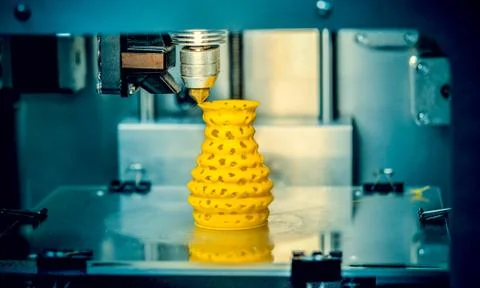 3d printer printing objects yellow form closeup. Stock Photos