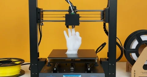3D printer prints model hands made of white plastic on yellow background. Video stock 126409567