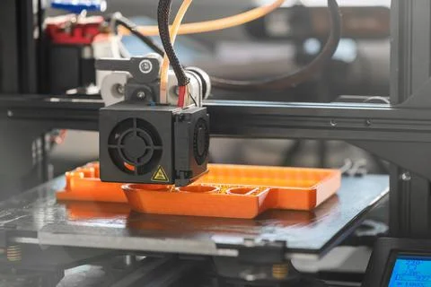 The 3D printer prints orange plastic model Stock Photos