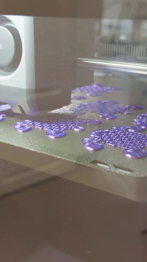 3D printer producing purple plastic parts on build plate inside enclosed Stock Footage 346558775