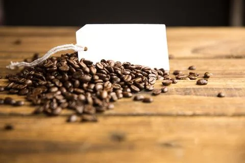 3D render showing mound of roasted coffee beans on rustic table with blank tag, Stock Photos