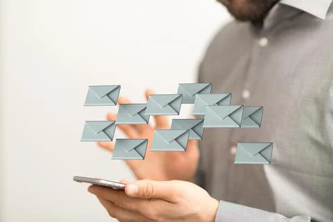 A 3D rendering of digital envelopes floating over hand holding a phone- onlin Stock Photos