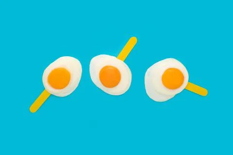 A 3D rendering of fried eggs on ice cream stick isolated on a blue background Stock-Illustration