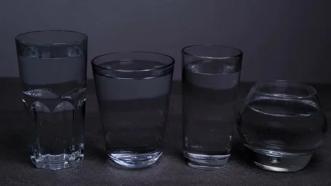 4 different glasses of water on a gray concrete background Stock Footage 167284909
