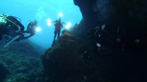 4 diver at the exit of the crack under the rocks, Ustica, Mediterranean sea Stock Footage 126906977