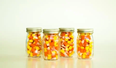 4 jars of candy corn on a solid background Foto stock