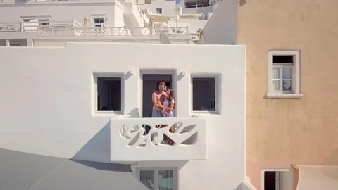 4 K aerial view young couple standing on hotel balcony in santorin Stock Footage 80267352