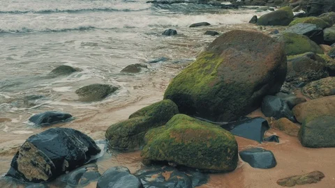 4 k Atlantic coast with rocks of differnt colour, orange sand and waves of ocean Stock Footage 93373809