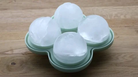4 large round ice cubes balls in a green silicone mold at home indoors. Stock Footage 340147095