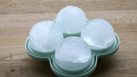 4 large round ice cubes balls in a green silicone mold at home indoors. Stock Footage 340147155