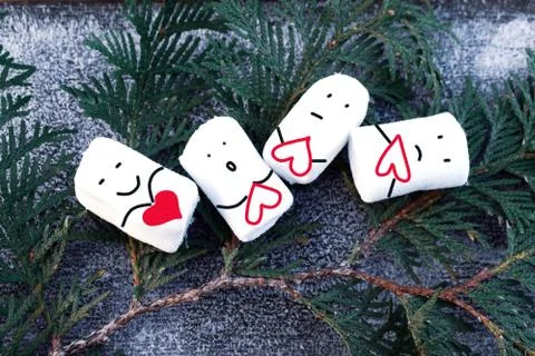 4 marshmallows lie with painted faces and hearts. Stock Photos