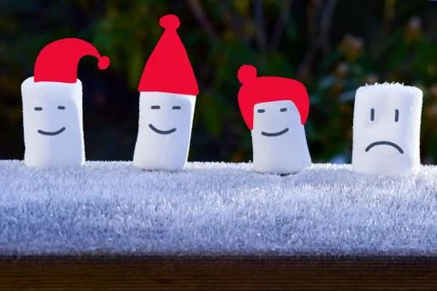 4 marshmallows stand with painted faces and red caps. Stock Photos