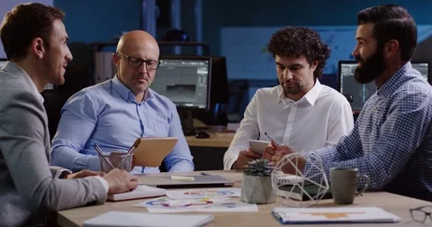 4 men office workers sitting at the table and discussing happily their work with Stock Footage 82473669